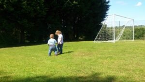 Two Small Children Holing Hands In A Field