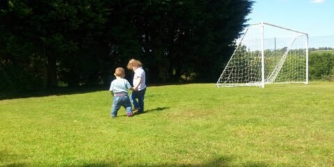 Two Small Children Holing Hands In A Field