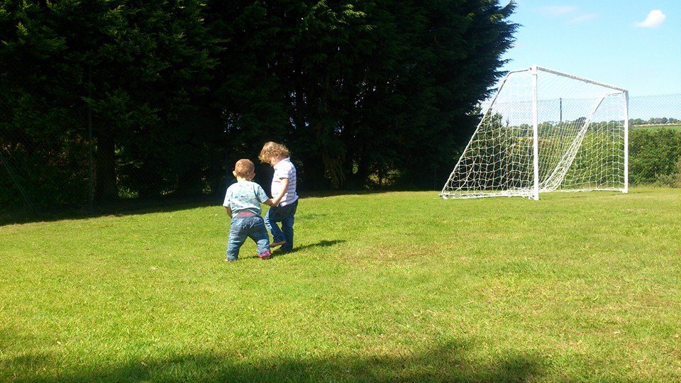 Two Small Children Holing Hands In A Field